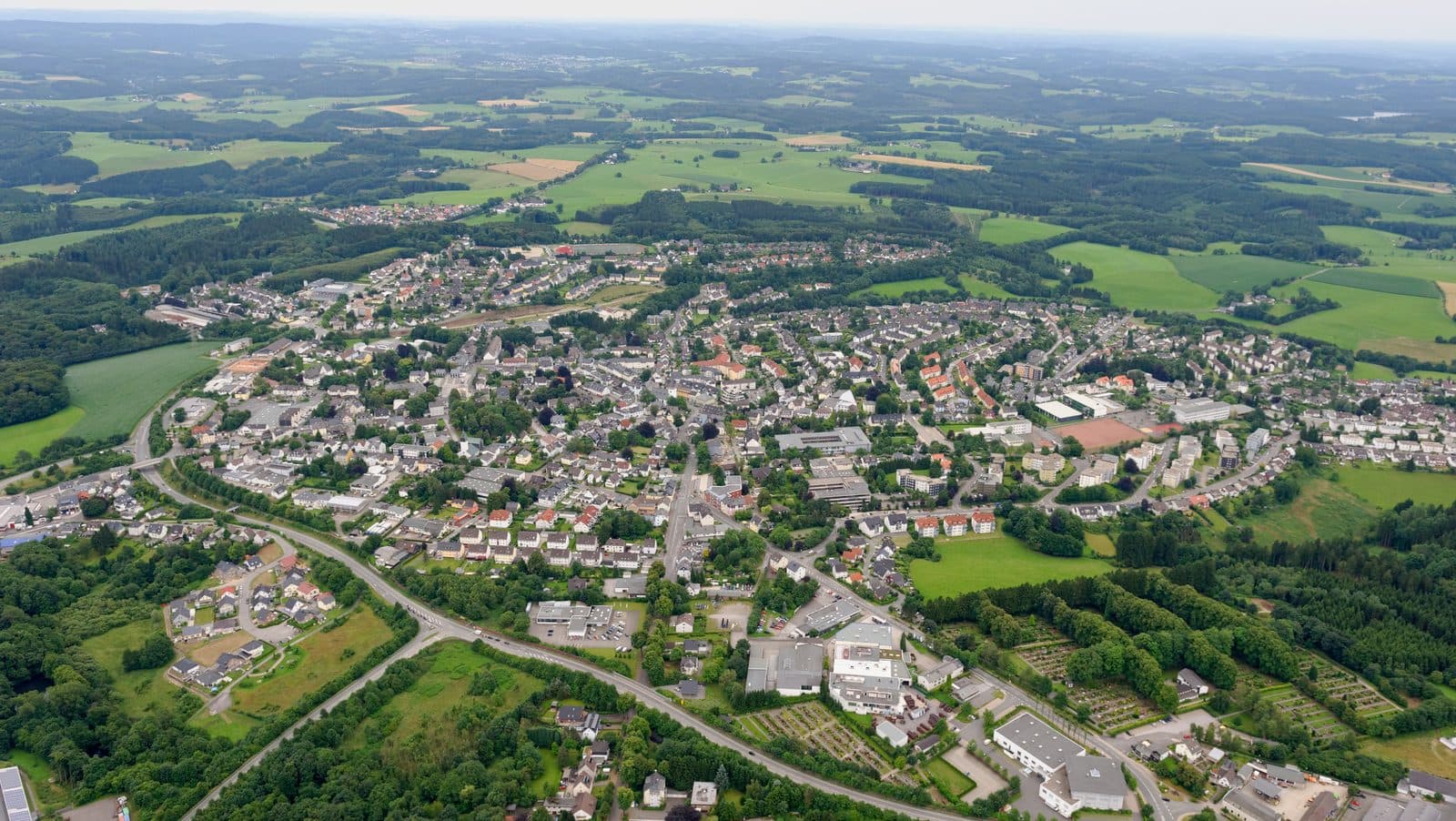 Luftaufnahme der Halveraner Kernstadt mit Bebauung am Hang und umliegenden Waeldern